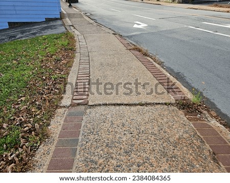 A weathered sidewalk with brick running along either side.
