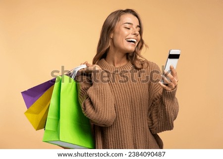 Young smiling attractive woman holding shopping bags, smartphone using mobile app shopping online with sales isolated on background. Black Friday, internet store 