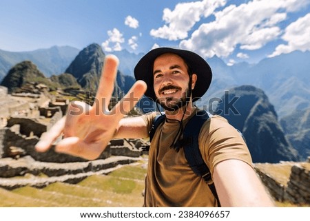 Happy young man taking selfie portrait at Macchu Picchu in Peru. Adventurer male enjoying vacation in South America. Royalty-Free Stock Photo #2384096657