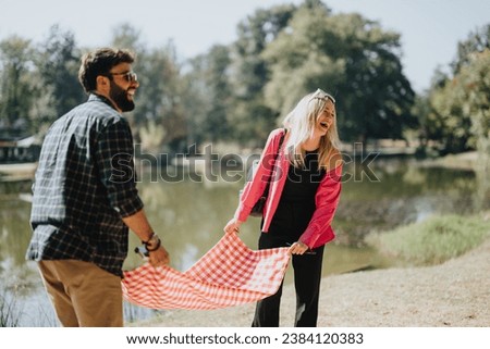 Carefree friends have a fun conversation in a sunny city park surrounded by nature during the weekend. They enjoy each others company, socializing and relaxing in a positive and playful atmosphere. Royalty-Free Stock Photo #2384120383