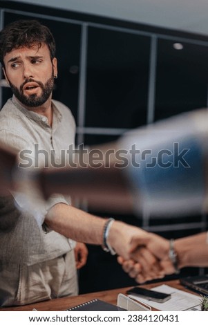 A multicultural group of business colleagues bidding farewell, shaking hands, and hugging as one employee leaves for a new job, marking their last day at work. Royalty-Free Stock Photo #2384120431