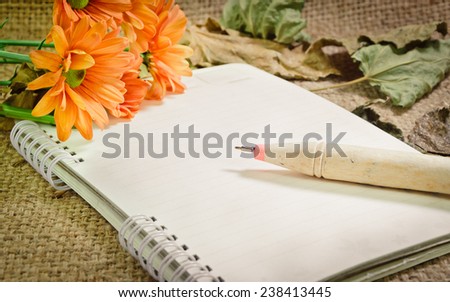 Paper, notebooks, pens with orange flowers on the table, vintage retro style.