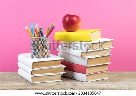 Books stacking. Books on wooden table and pink background. Back to school. Copy space for ad text