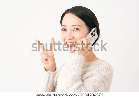 Asian middle aged woman with the smartphone peace sign gesture in white background