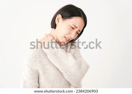 Asian middle aged woman having stiff shoulders in white background Royalty-Free Stock Photo #2384206903
