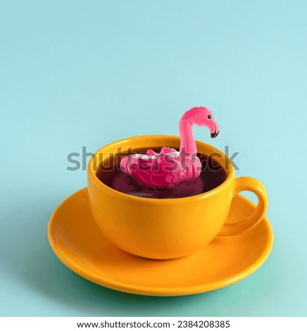 Pink inflatable flamingo swimming in yellow coffee cup on pink background. Minimal art creative poster.