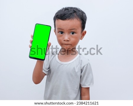 little asian boy holding a phone in his hand with a green screen