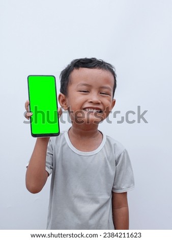 little asian boy holding a phone in his hand with a green screen