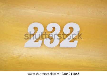 The golden yellow painted wood panel for the background, number 232, is made from white painted wood. Royalty-Free Stock Photo #2384211865