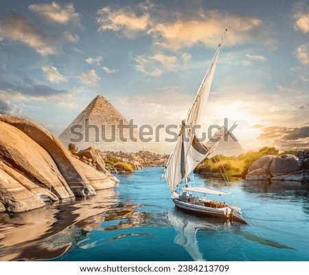 River Nile and boats at sunset in Aswan and pyramids Royalty-Free Stock Photo #2384213709