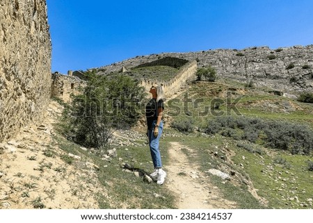A girl against the background of the Gunib fortress. A protective wall. Russia, Dagestan. June 2021
