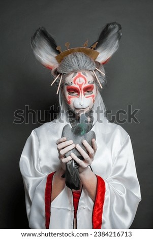 Fashion portrait of young actress woman with animal makeup, mask and stage asian costume standing on black background. Halloween, carnival, performance and theater concept