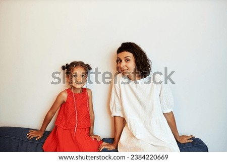 Funny picture of elder sister and naughty little girl with cute hairstyle with oops facial expression after making mess or breaking vase, trying to keep it to herself to avoid punishment