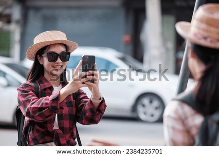 Asian female tourist takes a photo of a female friend while touring the city center.