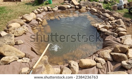 water jet falling on homemade pond in the garden. make pond at home step by step with rocks and cloth