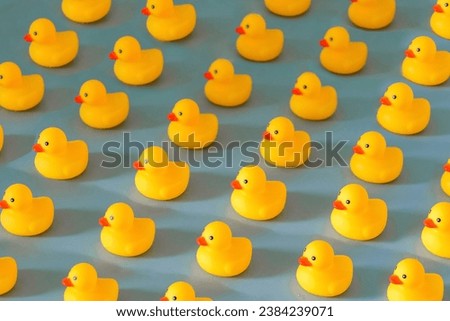 Many yellow rubber ducks in rows on blue background, fun community, family, get one’s ducks in a row, organisation concept