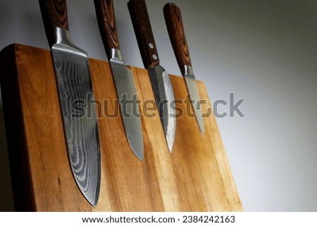 Japanese knives with blades made of beautifully textured Damascus steel on a wooden knife block.