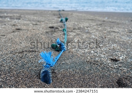 Close-up photo of a traditional boat anchor using rope and old tires embedded in the beach sand
