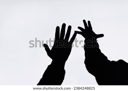 Shadow, silhouette, touch of hands of child and woman mother, family on white wall, background, showing love. Photography, gesturing concept, lifestyle.