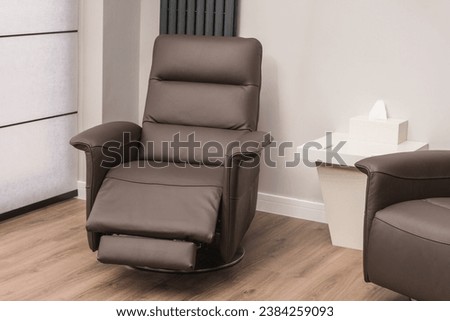 Brown leather recliner armchair in modern home. Solid surface coffee table and wood effect flooring. Royalty-Free Stock Photo #2384259093