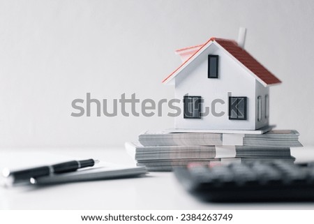 House with money. Concept of finance or refinance real estate. Symbol of house stands against background of us dollars. Property investment. Home mortgage loan rate. Saving money for retirement. Royalty-Free Stock Photo #2384263749