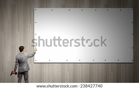 Rear view of businessman fixing white blank banner with drill