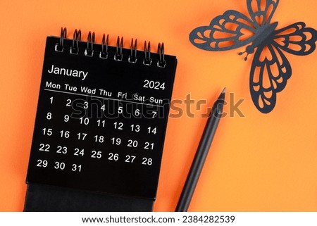 January 2024 desk calendar for the organizer to plan and reminder and butterfly paper on orange color background.