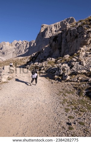 vertical photo, female hiker walking on a path in mountain lands