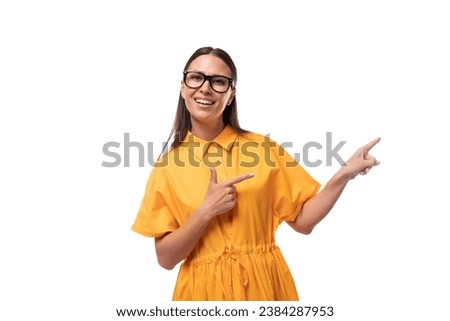 young well-groomed woman with black straight hair dressed in a yellow dress shows the news by pointing with her hand