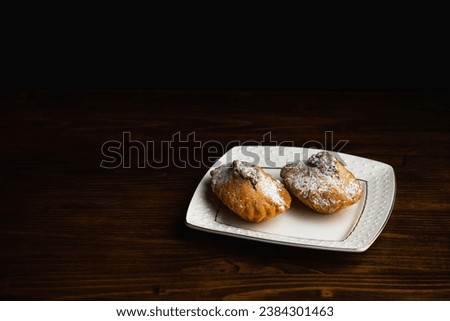 A picture of a muffin covered with icing sugar on a white plate