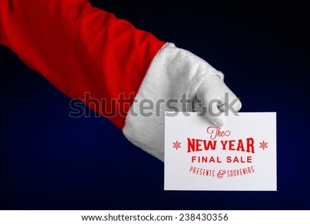 Christmas and New Year discounts topic: Hand of Santa Claus holding a white card with a Christmas discount on an isolated dark blue background