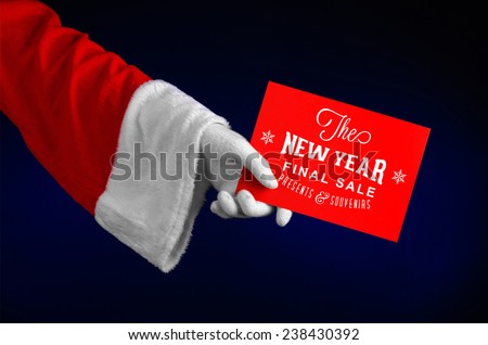 Christmas and New Year discounts topic: Hand of Santa Claus holding a red card with a Christmas discount on an isolated dark blue background