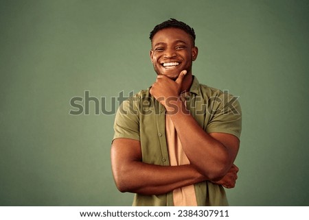 Frank human emotions. Joyful handsome man in casual wear sincerely smiling with hand to chin over green studio background. Friendly african american male feeling inspiration with new ideas. Royalty-Free Stock Photo #2384307911