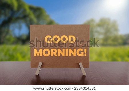 Good morning text on card on the table with sunny green park background. 