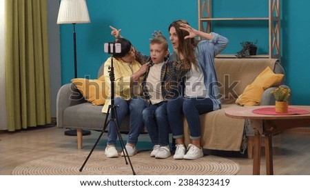 Close up of elderly woman her daughter and little boy sitting on the couch in the living room taking selfie on smartphone with tripod.