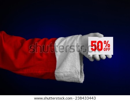 Christmas and New Year discounts topic: Hand of Santa Claus holding a white card with a 50 percent discount on an isolated dark blue background