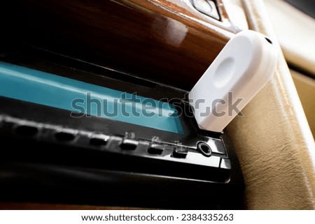 Close-up of a bluetooth car auxiliary adapter, connected to the stereo of a stylish car Royalty-Free Stock Photo #2384335263