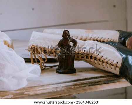 Close-up photo of two laced Victorian shoes, right behind a small icon object of a character Royalty-Free Stock Photo #2384348253