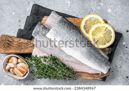 Fresh Raw Sea Bass fillets, Branzino fish with thyme and lemon. Gray background. Top view. Royalty-Free Stock Photo #2384348967