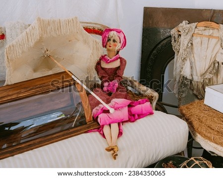 Old antique Victorian-Era children's doll, in a pink dress holding a vintage umbrella in a nice antique shop Royalty-Free Stock Photo #2384350065