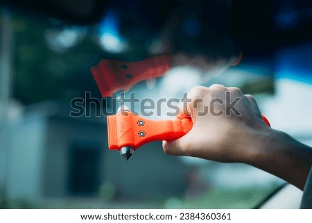 Close up Hand of Woman Uses Safety Hammer and Seatbelt Cutter in Car to Break Glass in Emergencies. Car Safety Red Hammers for Breaking Glass Windows in Case of Vehicle Emergency.