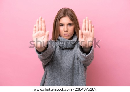 Young caucasian woman isolated on pink bakcground making stop gesture and disappointed