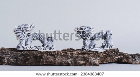 Ceramic dragons on tree bark on gray background for Chinese New Year web banner