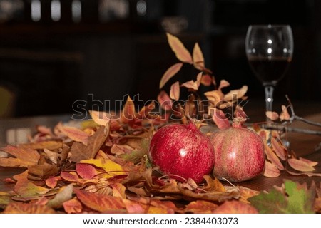 Yellow and red autumn leaves on a wooden floor, red wine and pomegranate in a glass.
