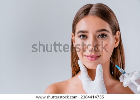 Woman face cosmetology or plastic surgery and beauty concept on background. Beautification with injections. Cosmetologist hands doing fillers with acid botox, anti-age procedure rejuvenation Royalty-Free Stock Photo #2384414735