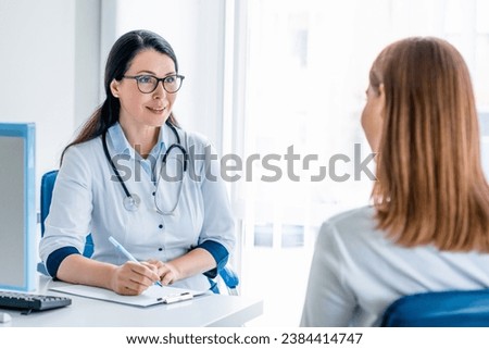 Adult doctor working and listening to the patient in modern clinic. General practitioner gynecologist visit, pregnancy planning, medicines prescription concept Royalty-Free Stock Photo #2384414747