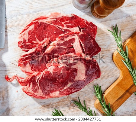 Unfinished beef steak with sprig of rosemary on cutting board. High quality photo