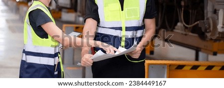 Young caucasian engineer man and woman or worker look blueprint and checking electric train for planning maintenance in station, transport and infrastructure, inspector or technician check transport.