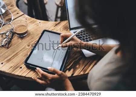 Faceless woman drawing diagram on tablet Royalty-Free Stock Photo #2384470929