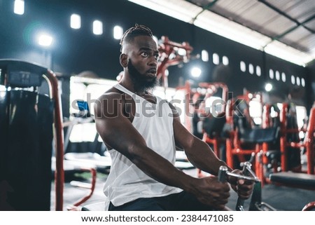 Black man sitting in gym near equipment with blur of lights